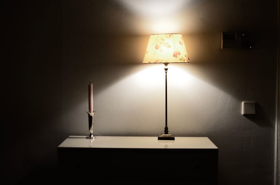 A softly lit room with a single warm lamp in the corner as evening settles in