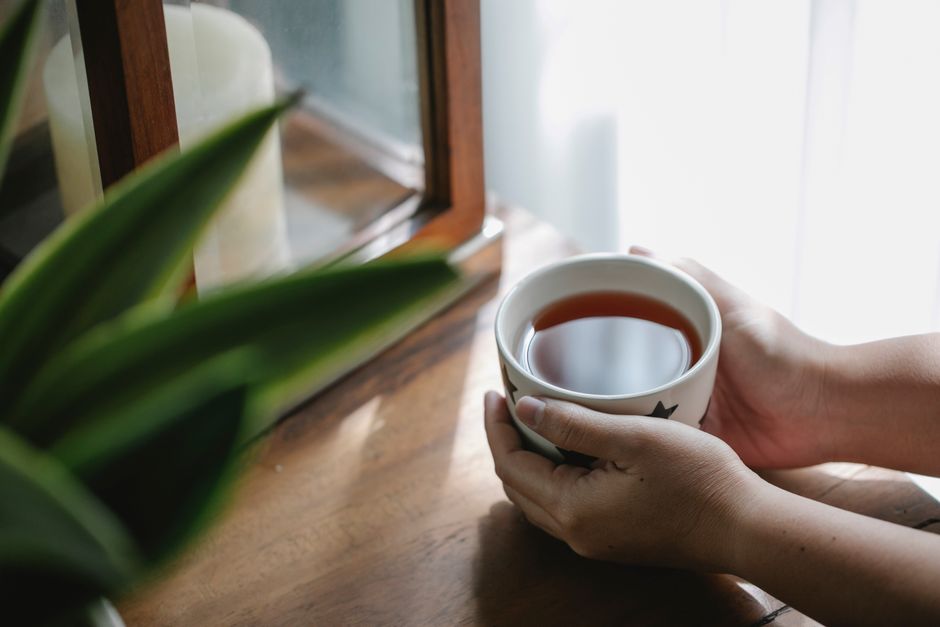 Hands wrapped around a warm mug in soft daylight