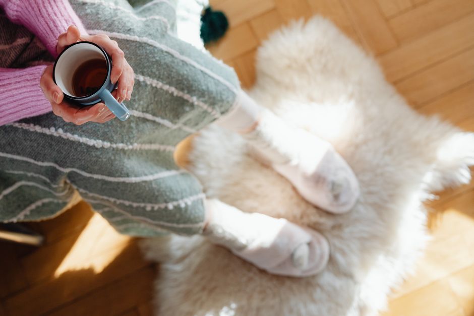 A pair of hands wrapped around a warm cup beside a window