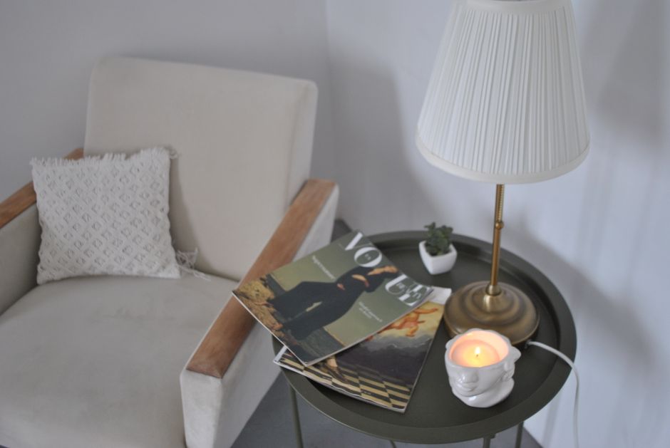 A person setting a small object on a side table in a softly lit living room corner