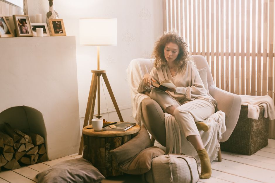 A person reading quietly by lamplight in an unhurried evening at home